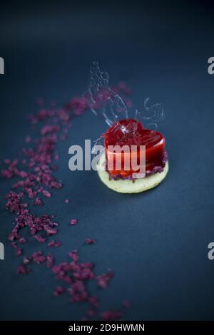 Herzförmige Mini-Kuchen mit rotem Karamell bedeckt und dekoriert mit Eine Karamellfigur Stockfoto