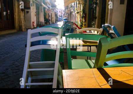 Am frühen Morgen, leere enge Gassen der alten mediterranen Stadt. Helle Sonne. Bunte Stühle und Tische in Cafés. Selektiver Fokus. Chania, Kreta, Griechenland Stockfoto