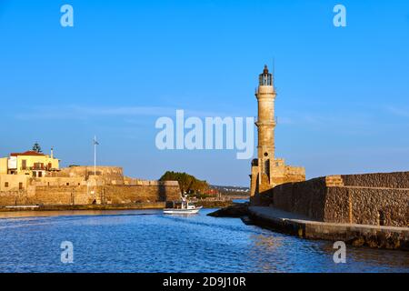 Fischerboot vorbei an berühmten Leuchtturm und Mauern des alten Hafens, Firka Festung, alten venezianischen Hafen von Chania, Kreta, Griechenland am Morgen. Goldene Stunde Stockfoto