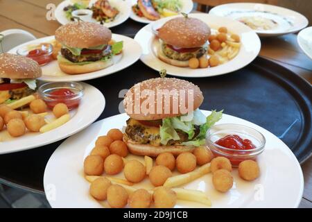 Teller mit Burgern und Kartoffeln auf Tablett im Restaurant Stockfoto