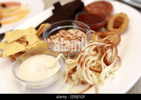 Blick auf verschiedene Biersnacks auf weißem Teller im Restaurant Stockfoto