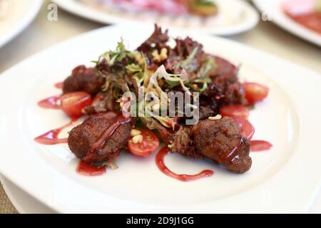 Warmer Salat mit Hühnerleber auf dem Teller im Restaurant Stockfoto