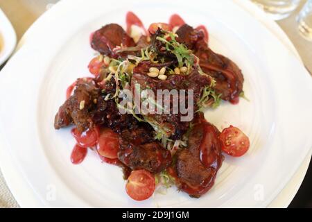 Warmer Salat mit Hühnerleber auf weißem Teller im Restaurant Stockfoto