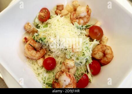 Caesar Salat mit Garnelen auf weißem Teller im Restaurant Stockfoto
