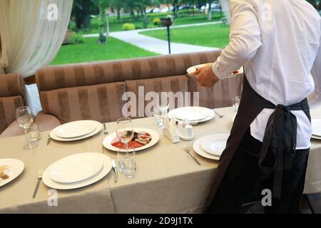 Kellner stellt Vorspeisen auf den Esstisch im Restaurant Stockfoto