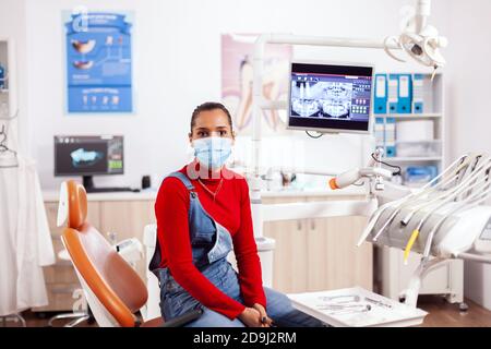 Patient mit Zähnen Gesundheit Hygiene Probleme tragen Gesichtsmaske in detal Klinik Blick auf Kamera. Frau in Stomatologie Schrank sitzen auf Stuhl warten Arzt für professionelle Expertise. Stockfoto