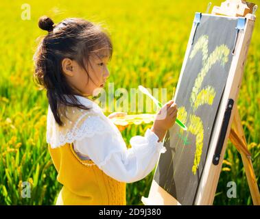 Eine Kindergärtnerin nimmt Kinder mit, um in den goldenen Reisfeldern zu malen, um den kommenden Herbst in Rugao City, der ostchinesischen Provinz Jiangsu, zu begrüßen. Stockfoto