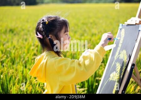 Eine Kindergärtnerin nimmt Kinder mit, um in den goldenen Reisfeldern zu malen, um den kommenden Herbst in Rugao City, der ostchinesischen Provinz Jiangsu, zu begrüßen. Stockfoto