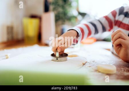 Glücklicher Junge, der einen Scone in der Küche vorbereitet Stockfoto