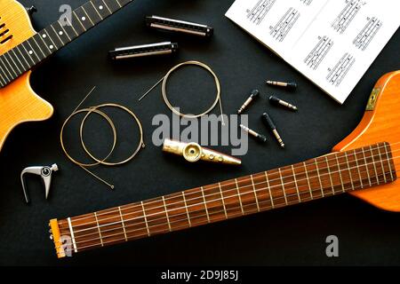 Musik-Flatlay mit einer akustischen klassischen Gitarre, Mundharmoniken, Kazoo und Spulen von Blechbläsergitarre Saiten. Stockfoto