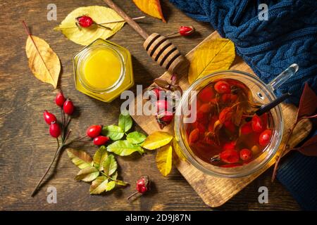 Gesundes Wintervitamingetränk. Heißer Hagebuttentee mit Honig und getrockneten Früchten auf einer Holzplatte. Draufsicht flach lagen Hintergrund. Stockfoto