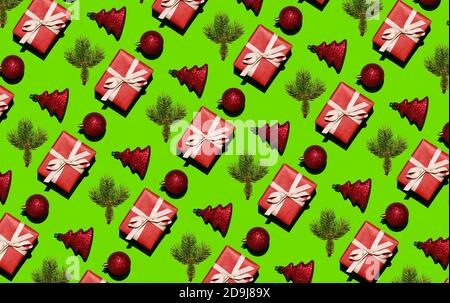 Weihnachtsmuster aus Tannenzweigen, Schachteln in rotem Papier und Weihnachtskugeln auf grünem Hintergrund. Weihnachten Hintergrund. Weihnachtliches Nahtmuster Stockfoto