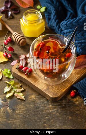 Gesundes Wintervitamingetränk. Heißer Hagebuttentee mit Honig und getrockneten Früchten auf einer Holzplatte. Speicherplatz kopieren. Stockfoto
