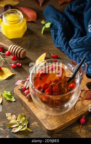 Gesundes Wintervitamingetränk. Heißer Hagebuttentee mit Honig und getrockneten Früchten auf einer Holzplatte. Stockfoto