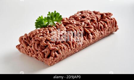 Pat von rohen pflanzlichen Basis veganen Hackfleisch mit garniert Petersilie in einer diagonalen Ansicht auf Weiß mit Copyspace Stockfoto