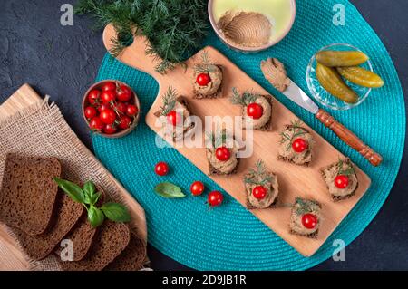 Kanapees mit Roggenbrot, Leberpastete, Kirschtomaten. Frühstückssnack. Draufsicht. Stockfoto