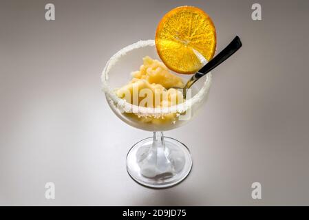 Orangenfruchteis in einem Tasse Glas mit karamellisiert Orange Scheibe und Teelöffel Stockfoto