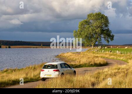 Einspurige Straße neben Lochindrob, Badenoch und Strathspey, Highland, Schottland. Weißes VW Polo Auto auf der Straße. Stockfoto