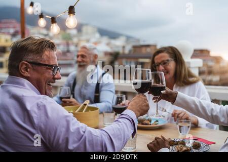 Fröhliche multirassische Senioren toasten mit Rotweingläsern zusammen auf House Patio Dinner - Ältere Lifestyle-Menschen Konzept Stockfoto