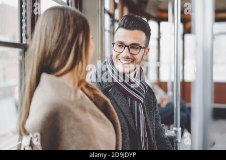 Glückliches Paar, das Gespräch hat, während man im Bus zur Arbeit geht - Junge Leute, die in der alten Straßenbahn Transport Stockfoto