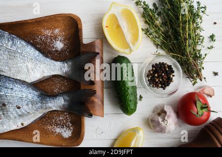 Meeresfrüchte. Zwei rohe Regenbogenforellen, mariniert mit Limette, Pfeffer, Gewürzen und Rosmarin auf Holzbrett. Gesunde Ernährung und Diät-Konzept. Stockfoto