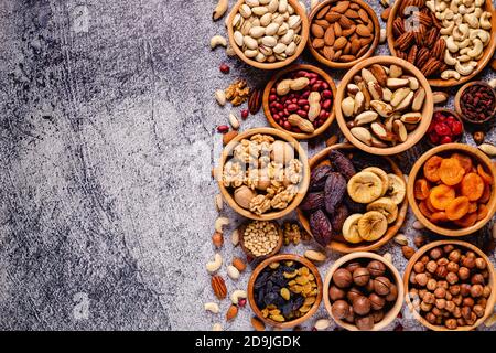 Verschiedene Nüsse und getrocknete Früchte in Holzschüsseln, Draufsicht. Stockfoto
