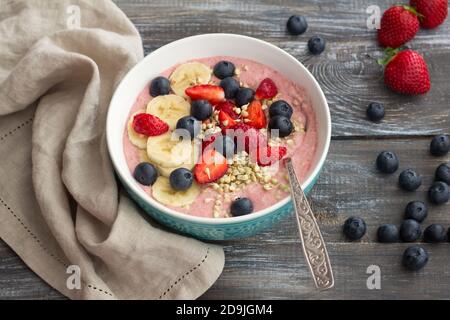 Gesundes rohes Frühstück: Porridge aus gekeimtem grünem Buchweizen mit Erdbeeren, Blaubeeren und Bananen auf einem Holztisch Stockfoto