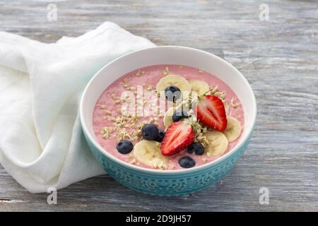 Gesundes Entgiftungsfrühstück. Smoothie Schüssel mit gekeimtem grünem Buchweizen, Erdbeeren, Blaubeeren und Bananen auf einem Holztisch, Freiraum Stockfoto