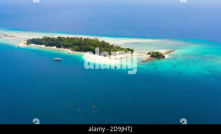 Blick von oben auf die kleine tropische kleine Insel Liguid im blauen Meer mit einem Korallenriff und dem Strand. Little Cruz Island, Philippinen, Samal. Stockfoto
