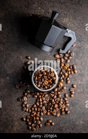 Kaffeebohnen und bialetti-Kaffeemaschine. Moka Topf auf schwarzem Tisch. Draufsicht. Stockfoto