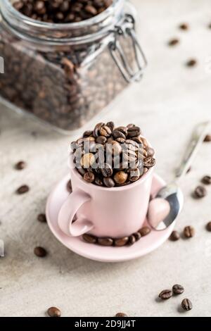 Geröstete Kaffeebohnen in Tasse auf weißem Tisch. Stockfoto