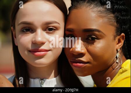 Nahaufnahme Gesichter von weißen kaukasischen Mädchen und schwarzen afroamerikanischen zusammen. Welteinheit, rassische Liebe, Verständnis in Toleranz und Rassen Vielfalt c Stockfoto