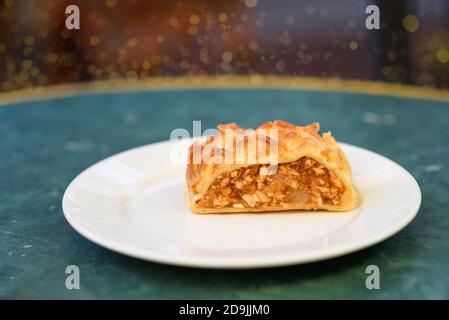 Schuppige Kruste und eine würzige Apfelfüllung, traditioneller Apfelstrudel oder Strudel auf marmorgrünem Tisch. Strudel köstlichsten Herbst und Winter Dessert, Essen für Weihnachten und andere Feiertage. Stockfoto