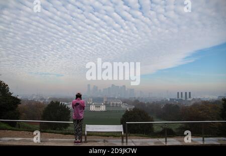 London UK 06 November 2020 EIN Läufer im pinken Trainingsanzug hält an diesem kalten Herbstmorgen in London für ein Selfie im dichten Nebel, der das Finanzviertel von Canary Wharf bedeckt. Paul Quezada-Neiman/Alamy Live News Stockfoto