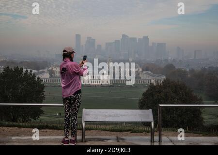 London UK 06 November 2020 EIN Läufer im pinken Trainingsanzug hält an diesem kalten Herbstmorgen in London für ein Selfie im dichten Nebel, der das Finanzviertel von Canary Wharf bedeckt. Paul Quezada-Neiman/Alamy Live News Stockfoto