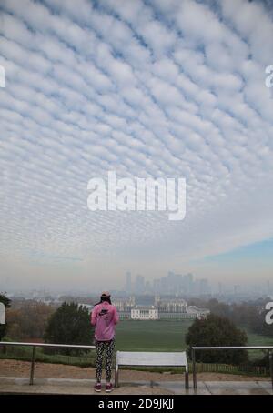 London UK 06 November 2020 EIN Läufer im pinken Trainingsanzug hält an diesem kalten Herbstmorgen in London für ein Selfie im dichten Nebel, der das Finanzviertel von Canary Wharf bedeckt. Paul Quezada-Neiman/Alamy Live News Stockfoto