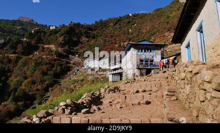 Namche Bazar, Nepal - 11/13/2019: Steinhäuser (Cafe, Lodge) auf dem Aufstieg zum Sherpa Dorf Namche Bazar, Khumbu, Himalaya auf dem Everest Base Camp Trek. Stockfoto