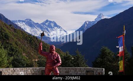 Namche Bazar, Nepal - 11/14/2019: Majestätisches Mount Everest-Massiv mit Lhotse und Nuptse mit violett gefärbter Tenzing Norgay-Statue davor. Stockfoto