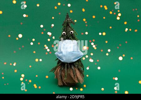 Weihnachtsbaum mit Schutzmaske und schönen Augen auf grünem Hintergrund, Bokeh Stockfoto