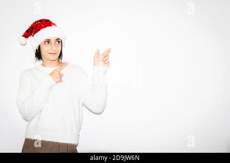 Cute kauätzische Frau in Weihnachten Outfit Punkte Zeigefinger auf der rechten weißen Leerraum. Werbung und Grüße Leerraum Konzept. Stockfoto