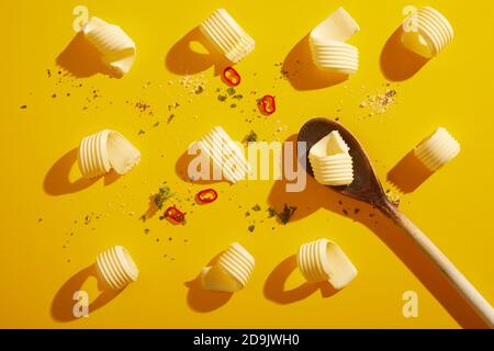 Flach legen Stillleben von eleganten Butter Locken auf gelb Mit dramatischen Schatten und verstreuten Gewürzen in einem Food-Styling Konzept Stockfoto