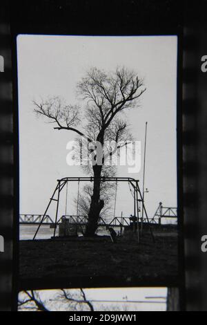 Feine Schwarz-Weiß-Fotografie einer Schaukel auf dem Spielplatz aus den 1970er Jahren. Stockfoto