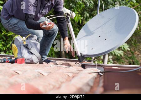 Techniker, der Satellitenschüssel und Fernsehantenne auf dem Dach installiert Stockfoto