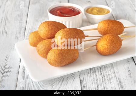 Maishunde mit Dip-Saucen auf weißem Servierteller Stockfoto