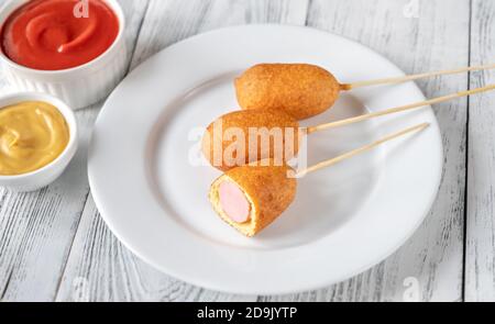 Maishunde mit Dip-Saucen auf weißem Servierteller Stockfoto