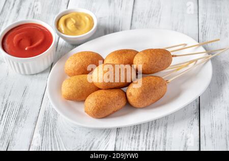 Maishunde mit Dip-Saucen auf weißem Servierteller Stockfoto