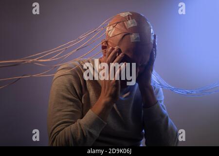Person mit Implantaten im Kopf erlebt Stress und Schrecken. Neue Technologien, Augmented Brain, Neuroschnittstelle und Virtualität. Stockfoto