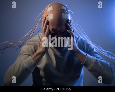 Person mit Implantaten im Kopf erlebt Stress und Schrecken. Neue Technologien, Augmented Brain, Neuroschnittstelle und Virtualität. Stockfoto