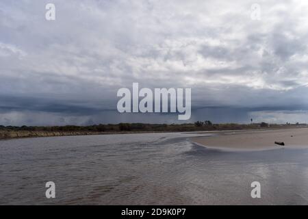 Flussmündung bei stürmischem Wetter. Starke Regenfälle können am Horizont über einem nahe gelegenen WWF Reserve in der Nähe von Rom, Italien gesehen werden Stockfoto