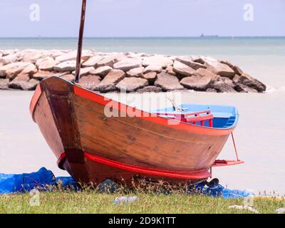 Fischer, der an einem regnerischen Tag in der Provinz Rayong in Thailand auf seinem traditionellen Holzboot arbeitete. Stockfoto